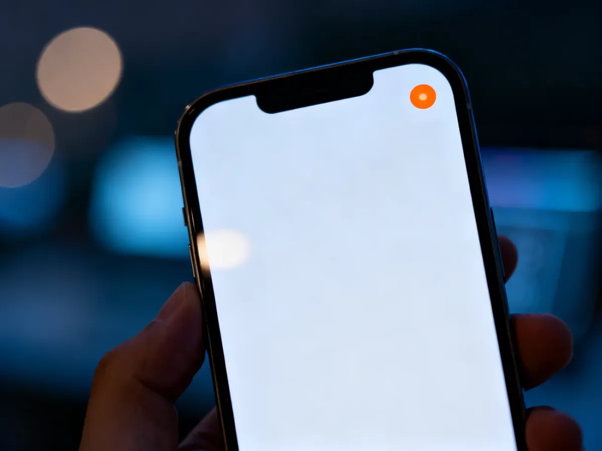 Pomarańczowa kropka w prawym górnym rogu ekranu iPhone'a, sygnalizująca aktywność mikrofonu.